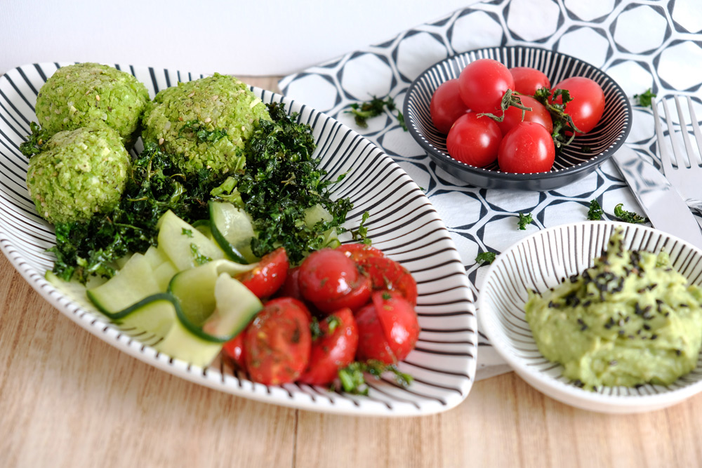 Salade met edamamefalafel, tomaat, komkommerlinten en krokante boerenkool. Met avocadospread